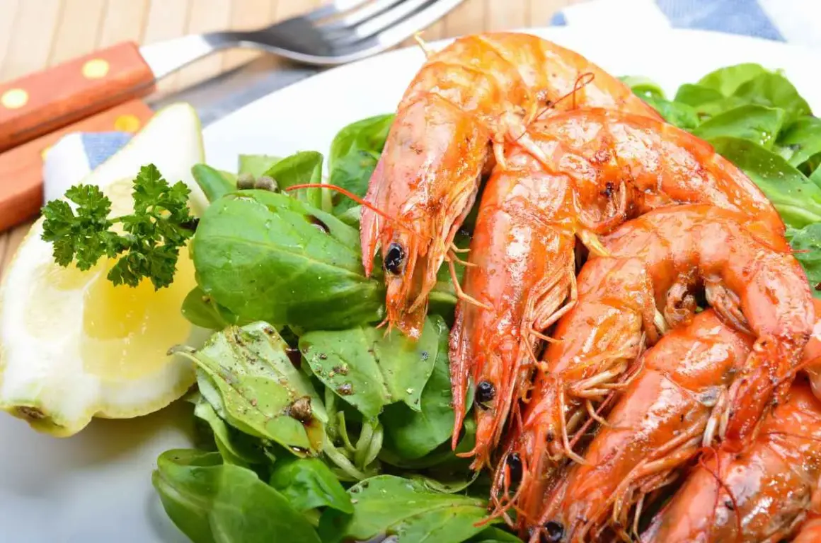 Gamberoni succulenti, pronti per la griglia, con un'insalata fresca e una fetta di limone. La marinatura per gamberoni alla griglia è il segreto del loro sapore.