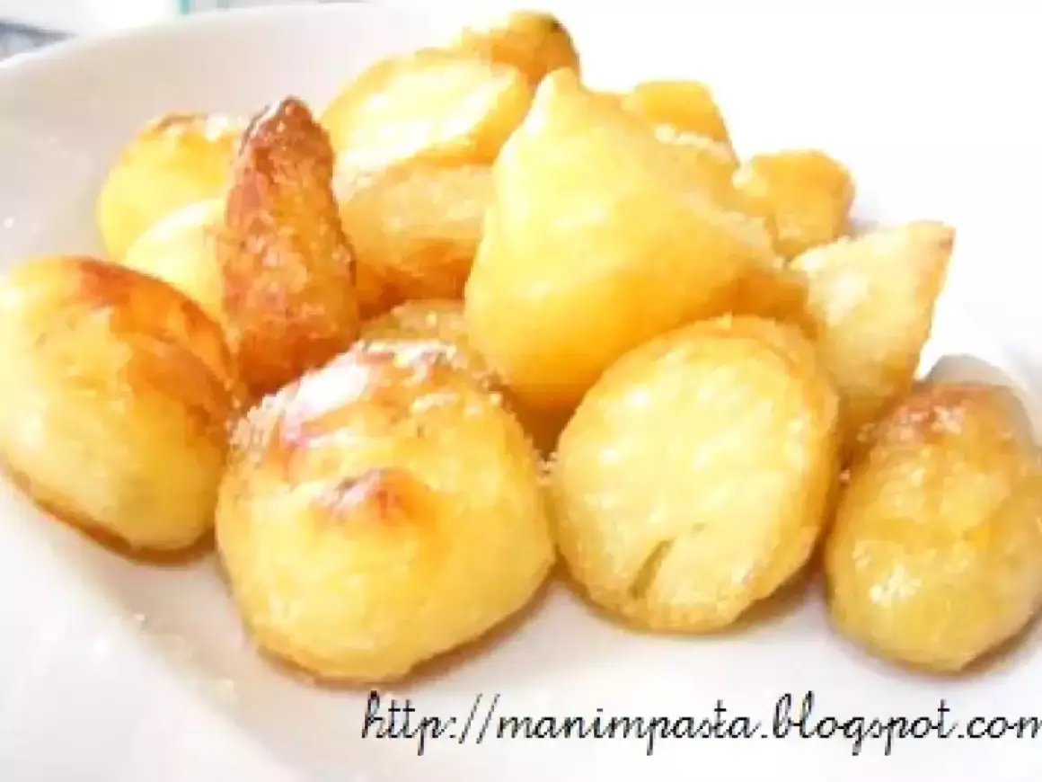 Un mucchio invitante di patate al forno dorate e croccanti, cosparse di un leggero velo di sale.