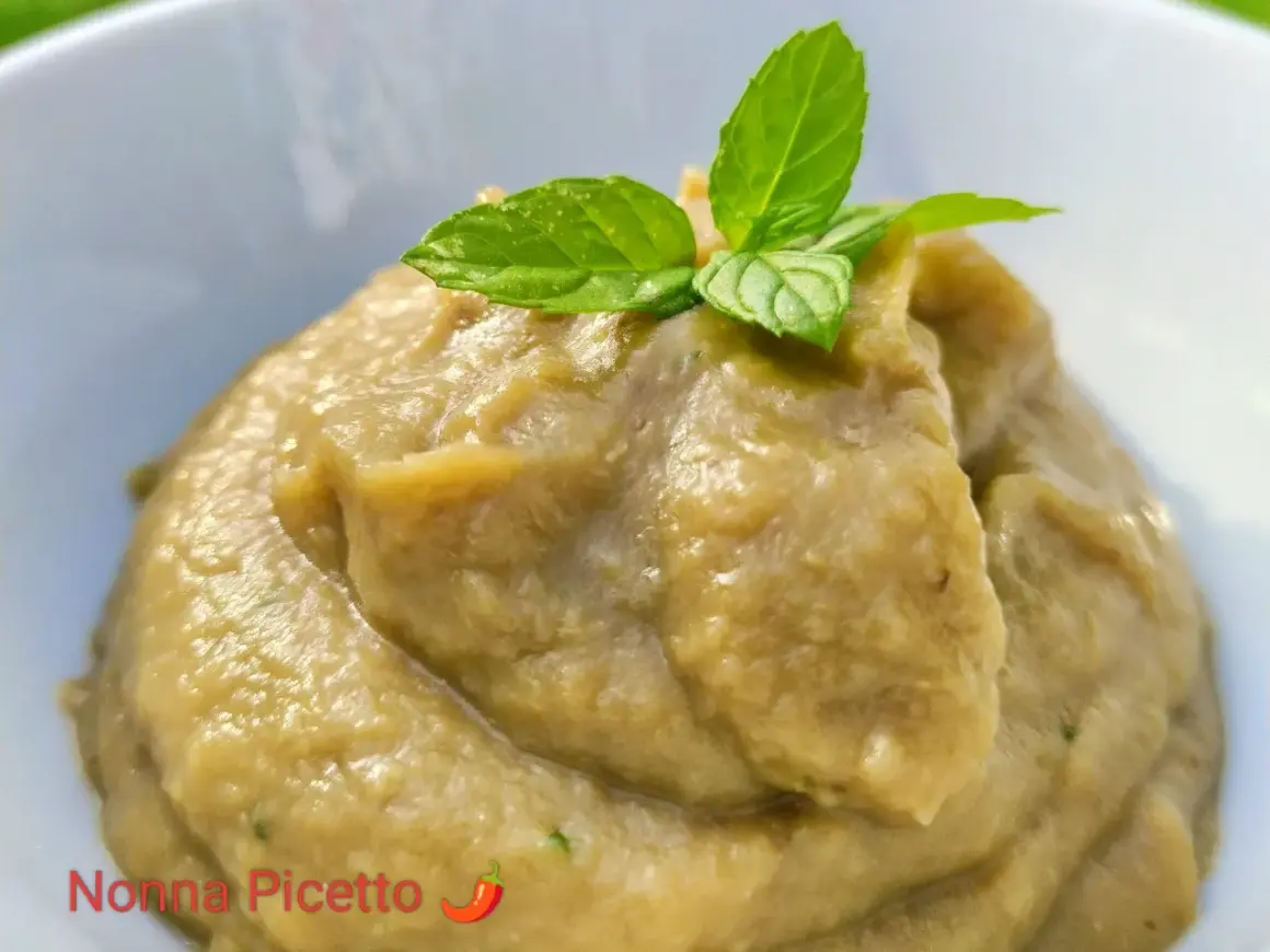 Un cremoso pesto di melanzane, guarnito con foglie di menta fresca, pronto per essere gustato.