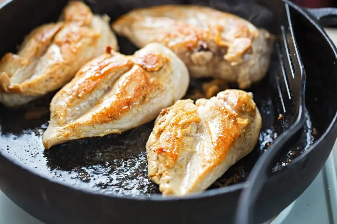Petto di pollo dorato e succulento che sfrigola in padella, pronto per essere gustato.
