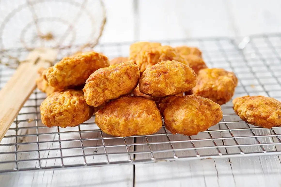 Nuggets fatti in casa dorati e croccanti, appena scolati su una griglia.
