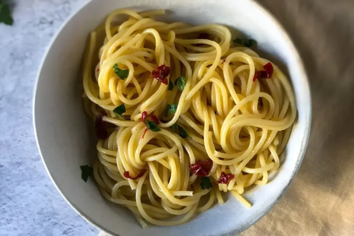 Spaghetti conditi con aglio, olio e peperoncino, guarniti con prezzemolo fresco. Un classico piatto italiano.