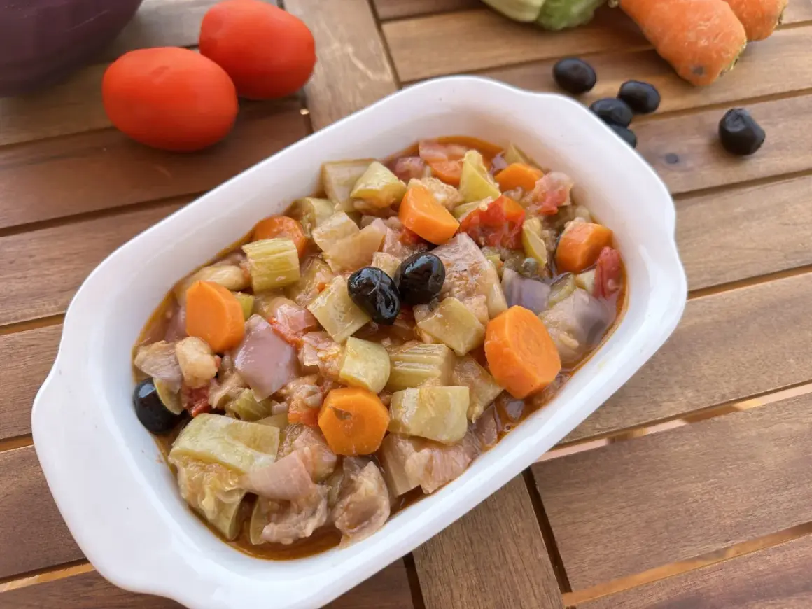 Un invitante piatto di caponata di verdure, con melanzane, carote, sedano e olive nere, pronto per essere gustato.