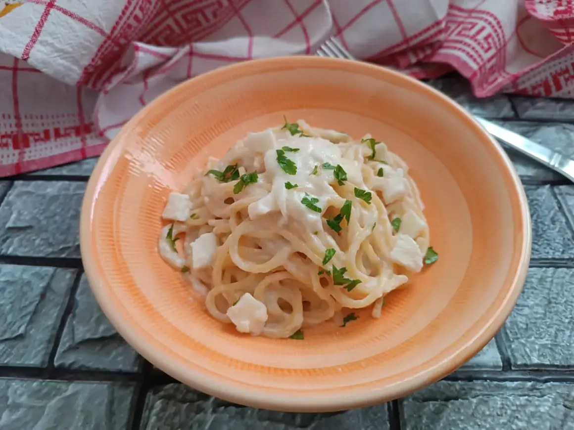 Spaghetti cremosi con cubetti di mozzarella di bufala e prezzemolo fresco, un piatto semplice e delizioso.