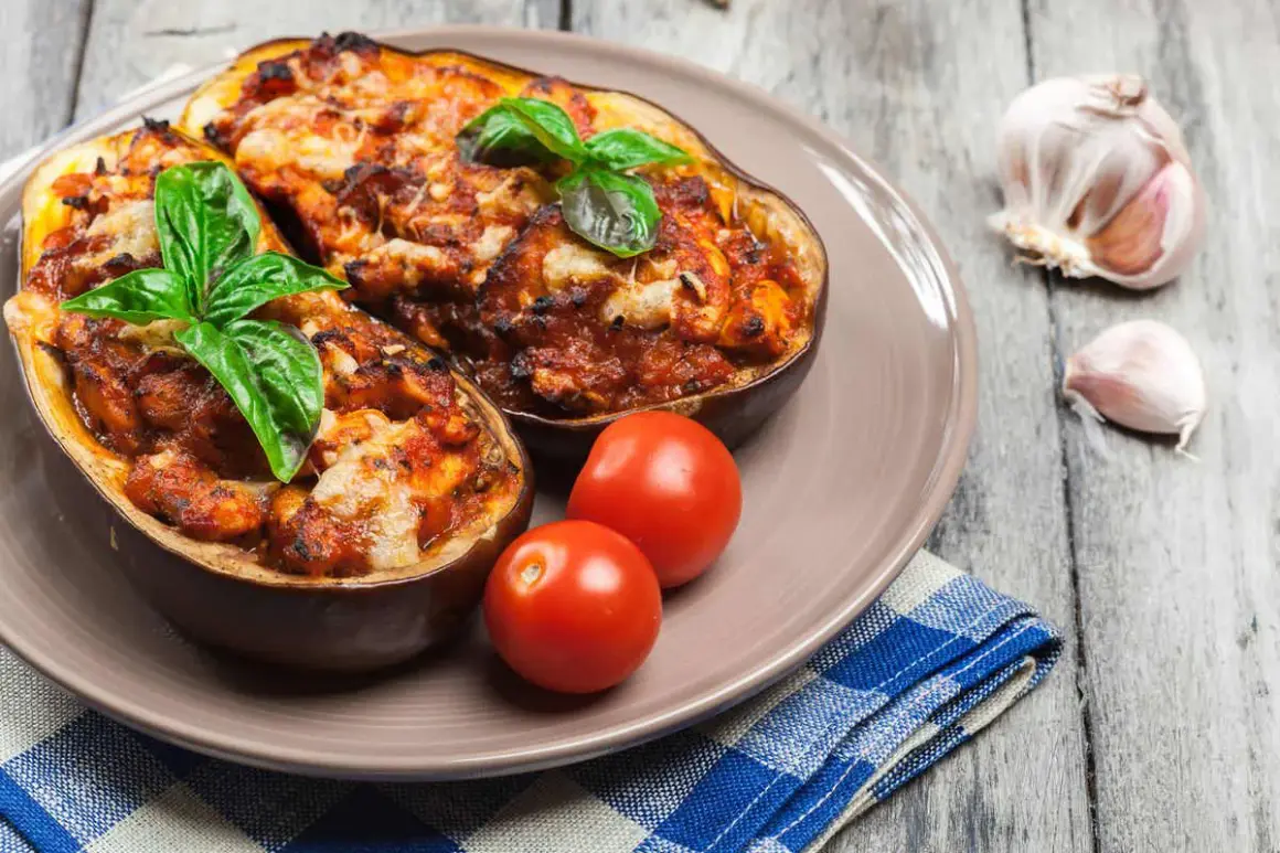 Melanzane alla siciliana, gustoso piatto con melanzane ripiene, pomodorini e basilico fresco, su un tavolo di legno.