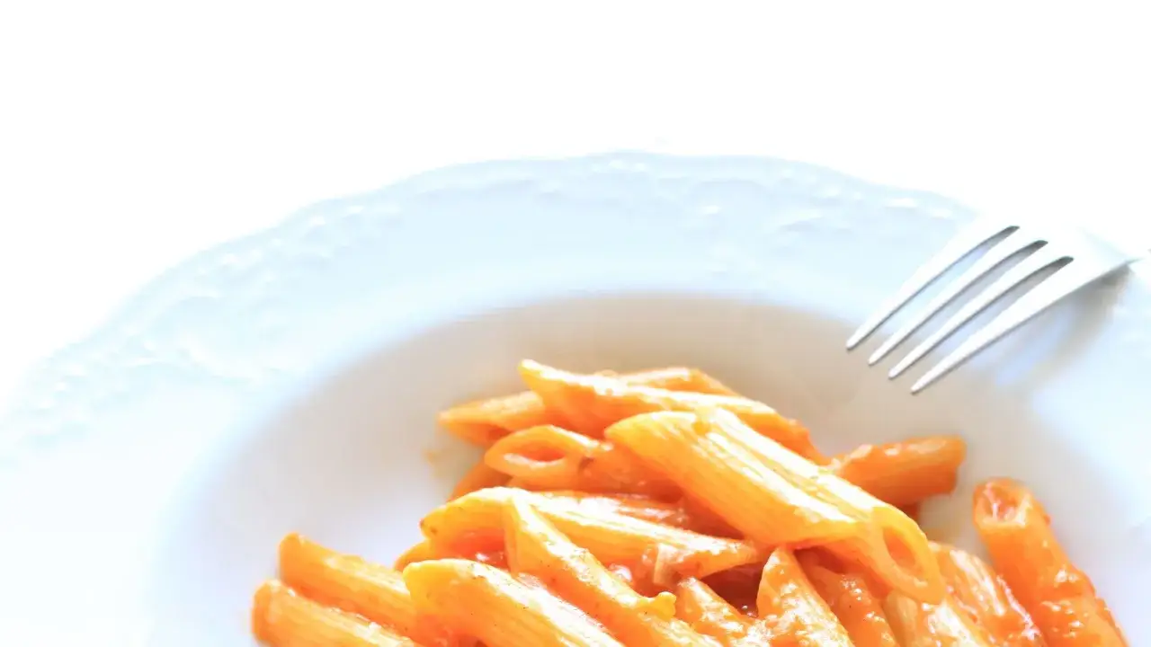 Piatto di penne alla vodka cremose, con una forchetta pronta a gustare questo classico italiano.