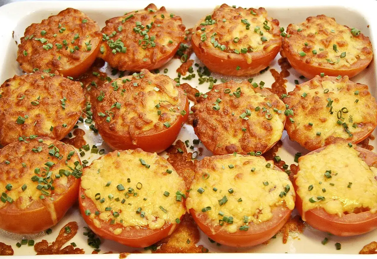 Pomodori al forno alla siciliana, ripieni e gratinati, guarniti con erba cipollina fresca.