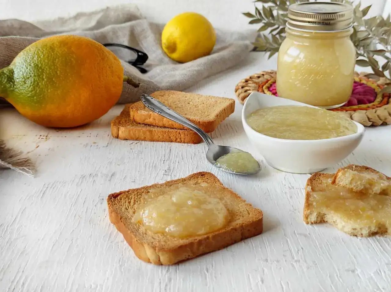Marmellata di limoni ricetta: limoni freschi, fette biscottate e un vasetto di deliziosa marmellata fatta in casa.
