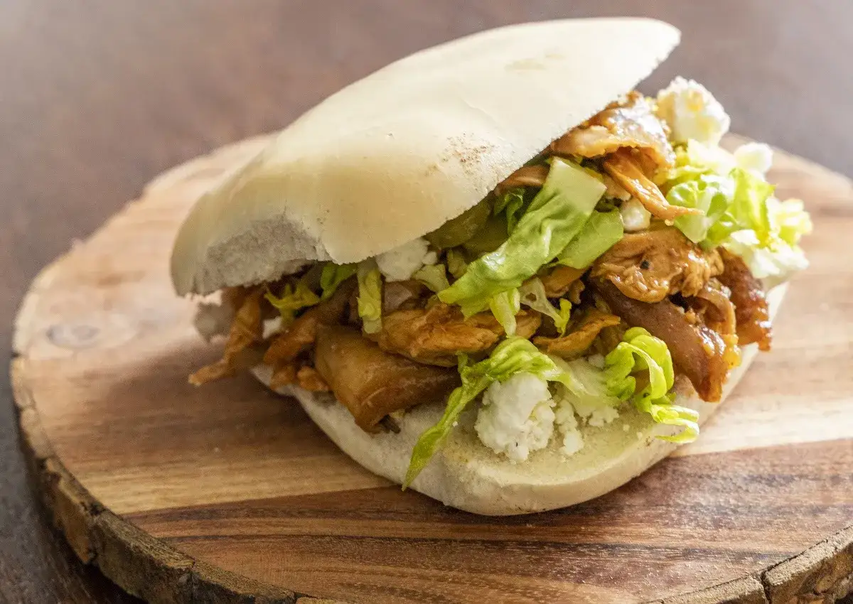 Panino con pulled chicken, lattuga e formaggio sbriciolato. Una deliziosa ricetta facile da preparare.