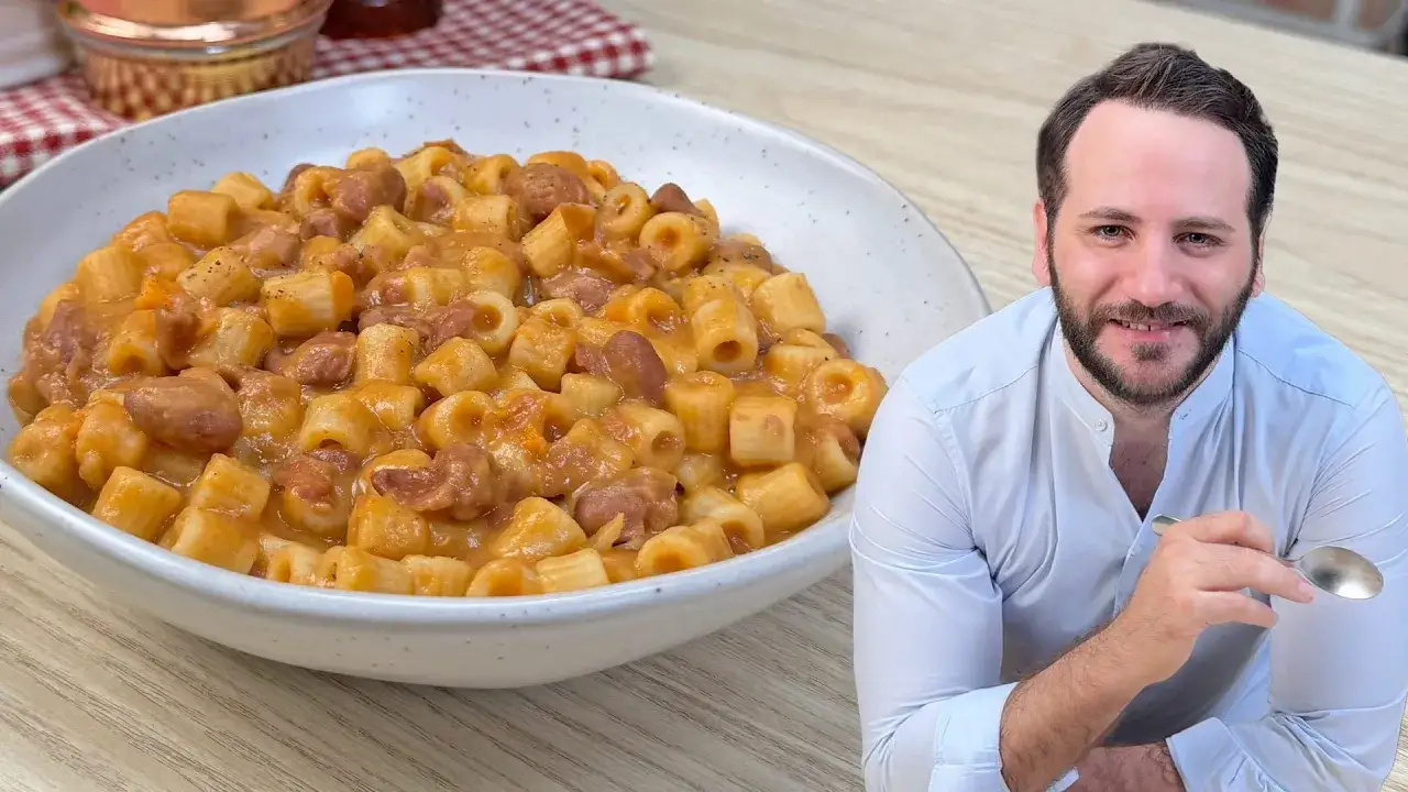 Un uomo sorride accanto a un piatto di pasta e fagioli in scatola, un classico comfort food.