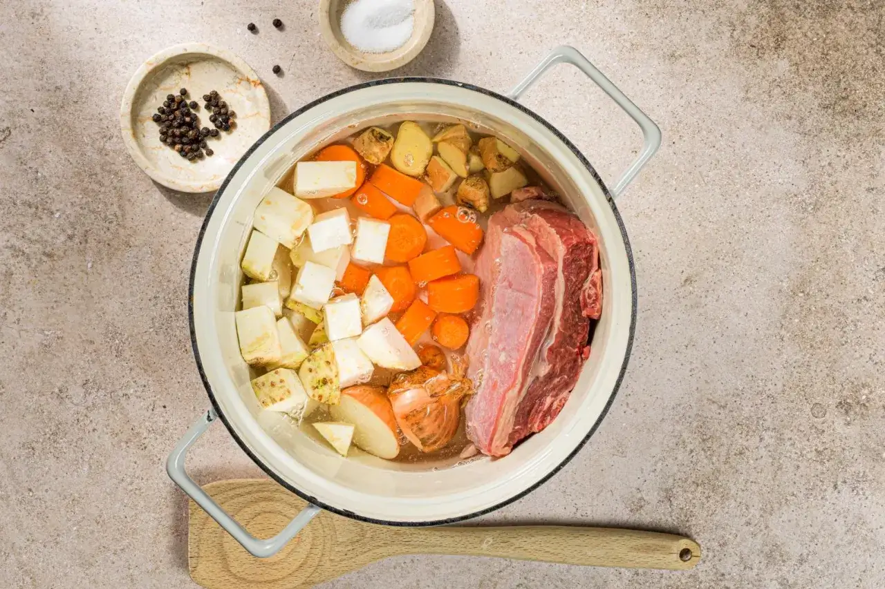 Ingredienti per un brodo di carne ricetta: carne, carote, sedano, cipolla e spezie in una pentola.