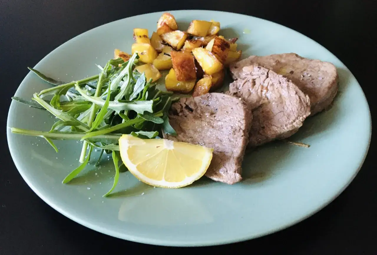 Piatto con paillard di vitello, patate arrosto, rucola e spicchio di limone.