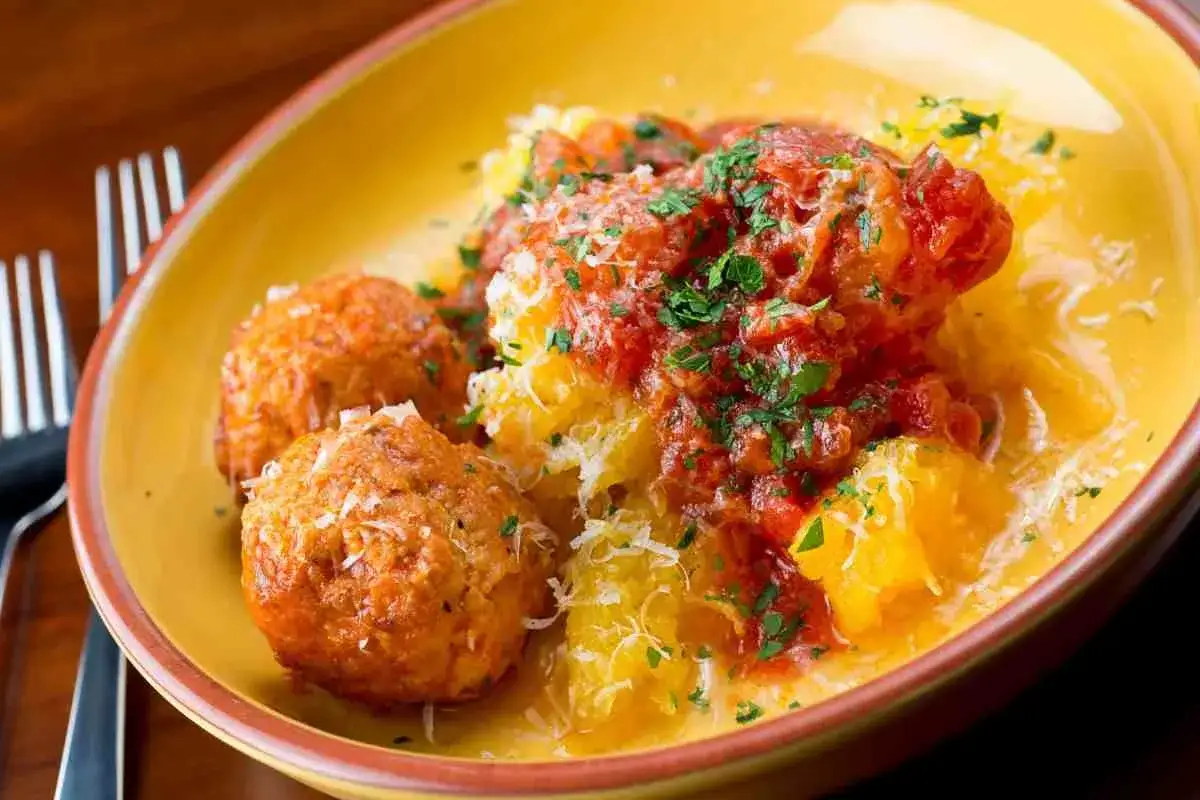 Tre polpette di carne dorate, servite su un letto di polenta cremosa, condite con sugo di pomodoro e prezzemolo fresco.