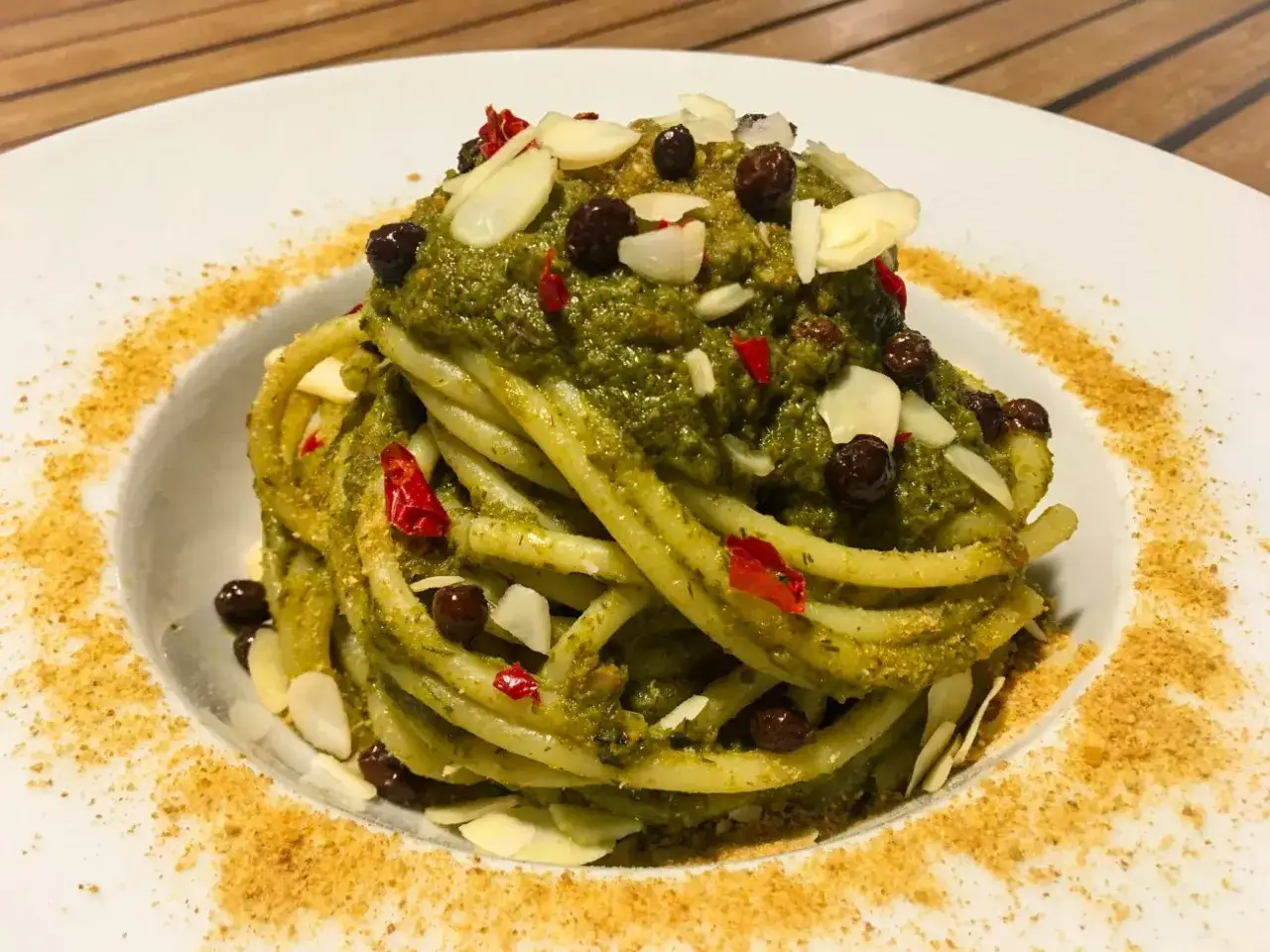 Un piatto di pasta con le sarde semplice in bianco, condita con un pesto verde, mandorle a lamelle, uvetta e peperoncino.
