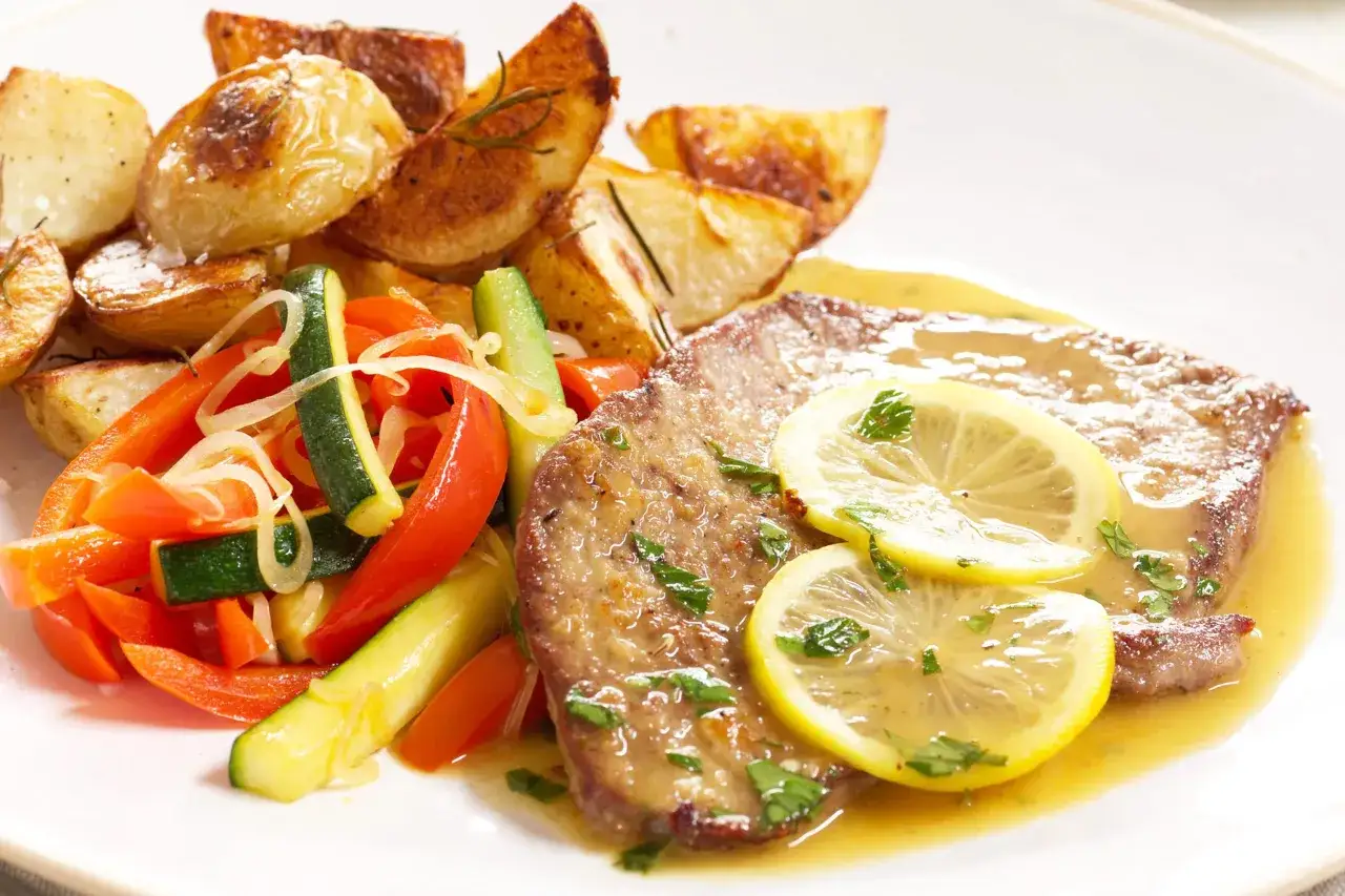Scaloppine al limone succulente con contorno di patate arrosto e verdure miste.
