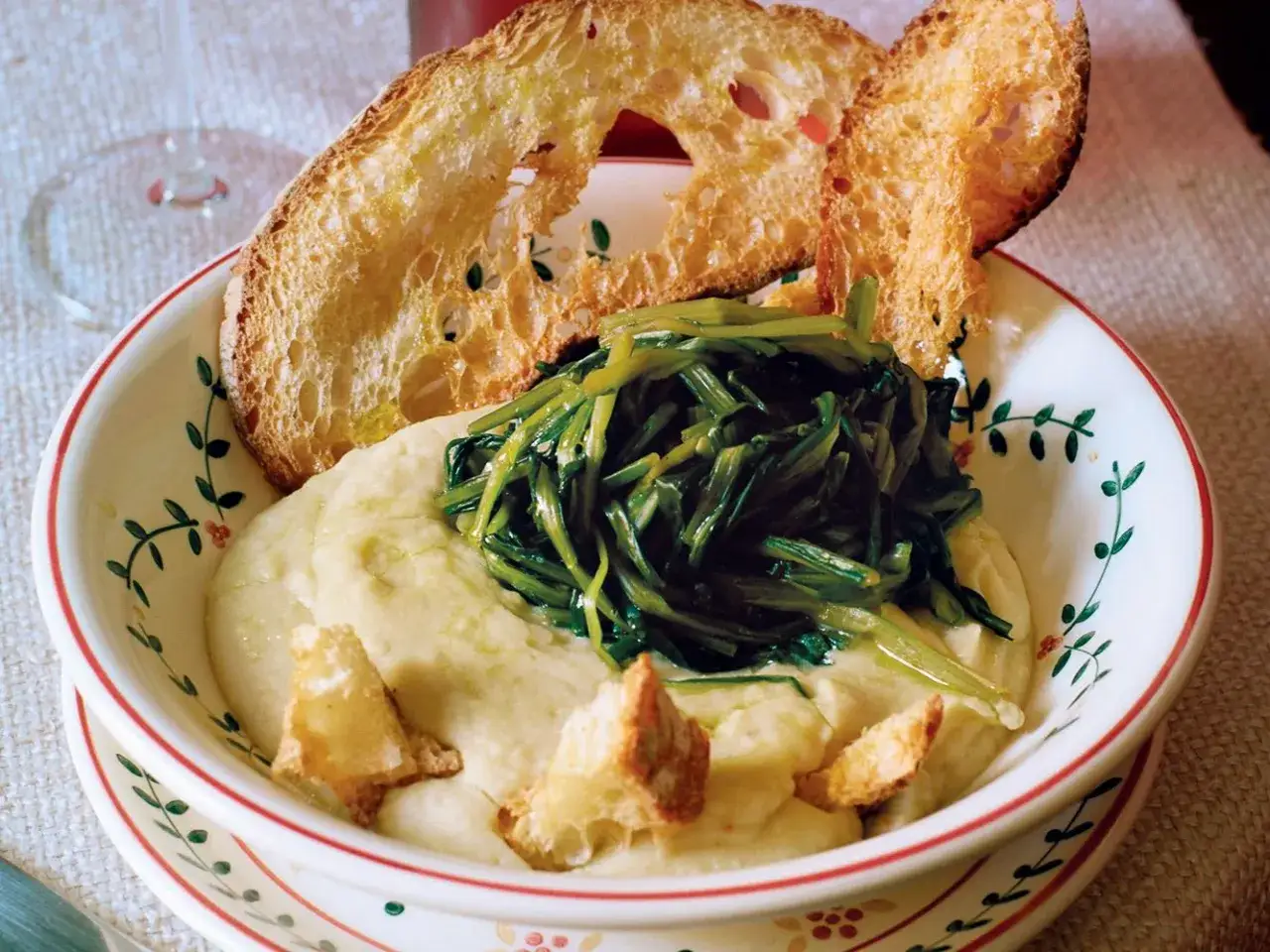 Piatto di fave e cicoria con crostini di pane abbrustolito. Un classico della cucina italiana, gustoso e salutare.