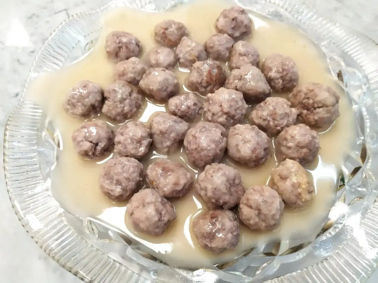 Polpette in bianco, morbide e succulente, servite in un piatto di vetro trasparente.