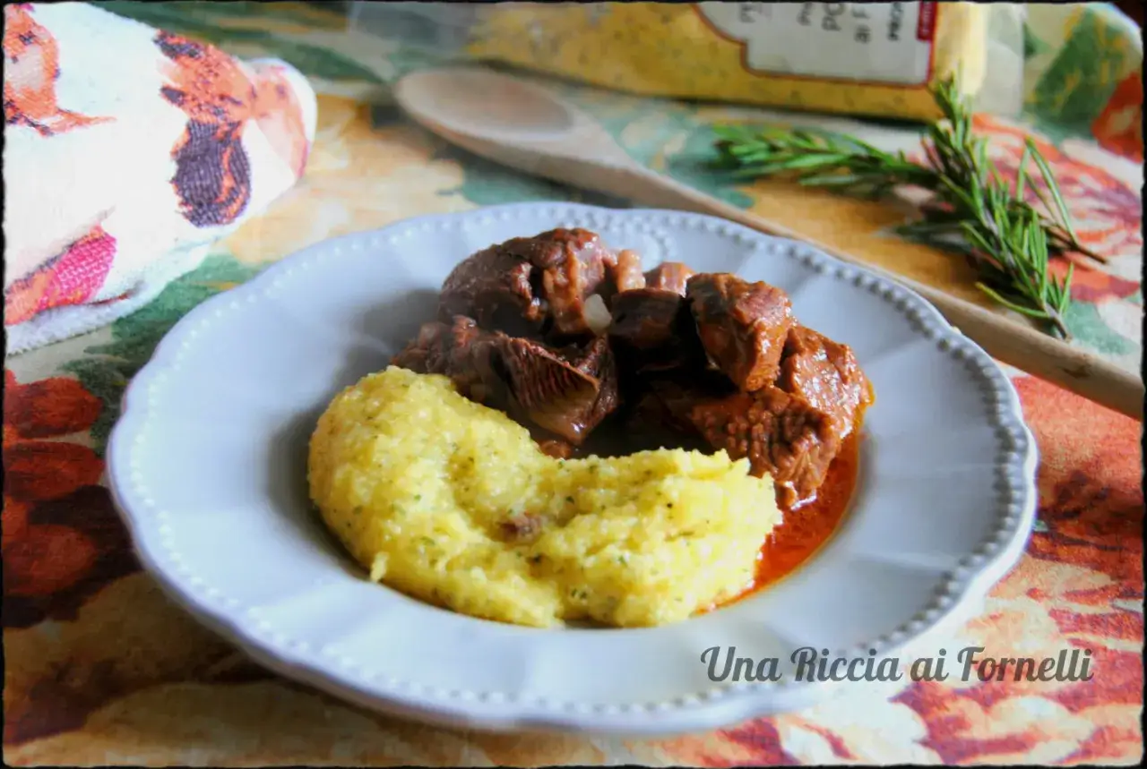Un saporito spezzatino di manzo con polenta cremosa, guarnito con rosmarino fresco. Un piatto che scalda il cuore.