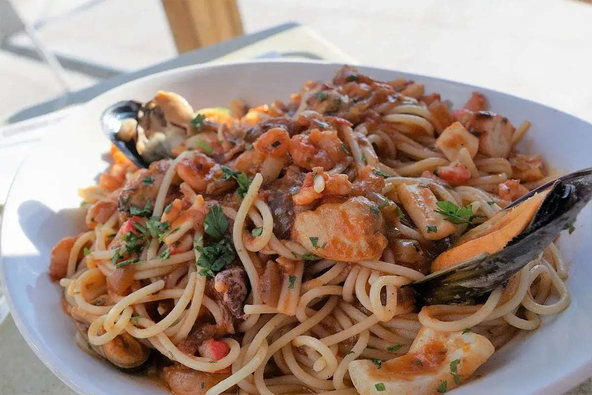 Spaghetti con un saporito ragù di pesce, ricchi di gamberi, calamari e cozze, guarniti con prezzemolo fresco.