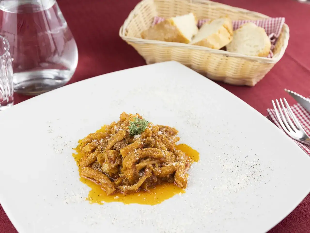 Un piatto di trippa alla fiorentina fumante, guarnito con erbe aromatiche e parmigiano, pronto per essere gustato con pane fresco.