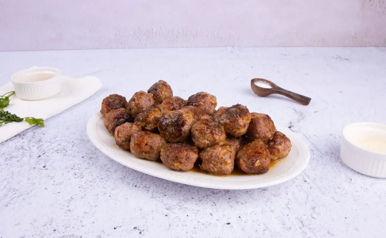 Polpette in bianco cremose in padella, dorate e succulente, servite su un piatto bianco.