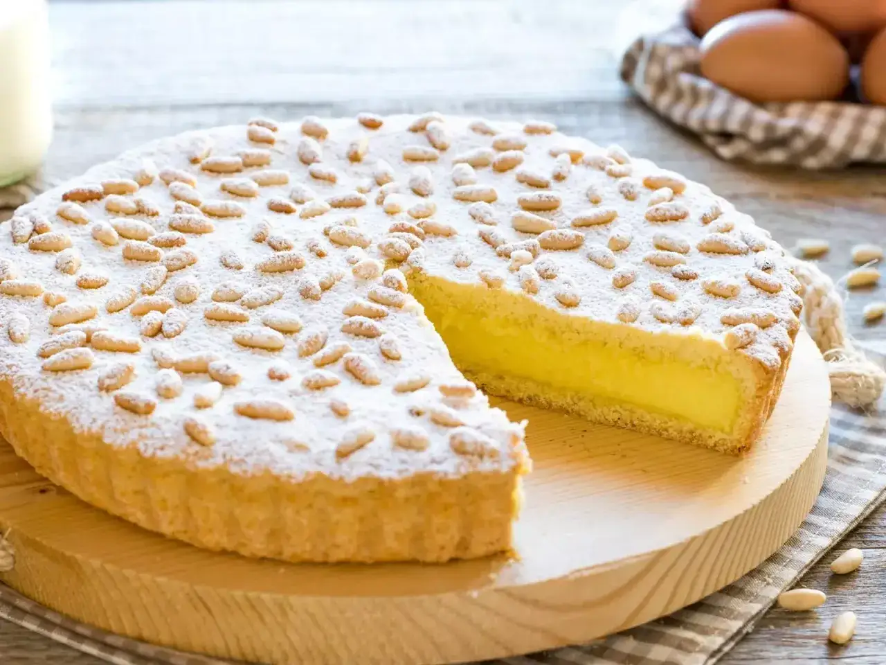 Una deliziosa torta della nonna, con crema gialla e pinoli tostati, cosparsa di zucchero a velo.