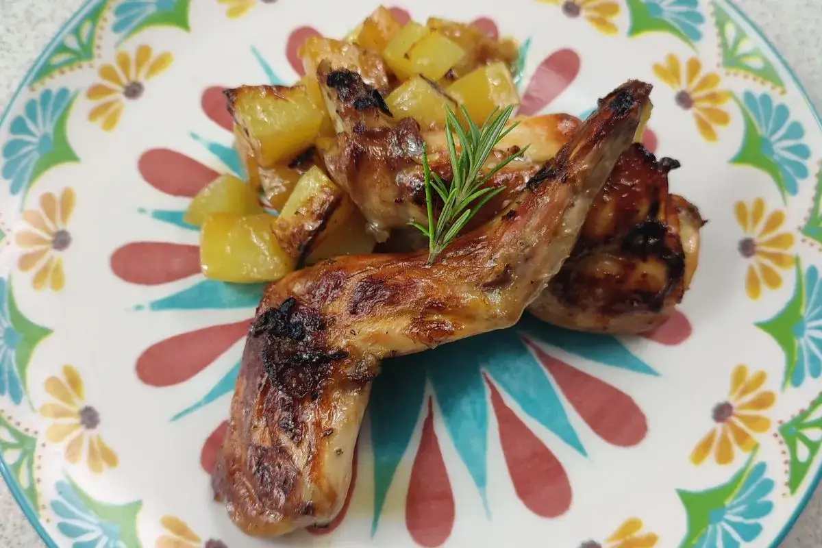 Delizioso coniglio al forno con patate arrosto e rosmarino su un piatto colorato.