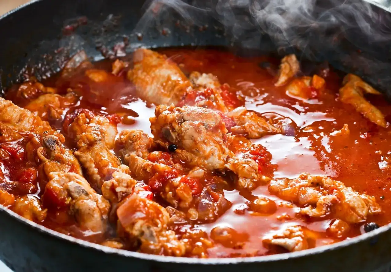 Carne alla pizzaiola morbida che sobbolle in padella, con pomodoro e spezie. Un profumo invitante si sprigiona dal piatto fumante.