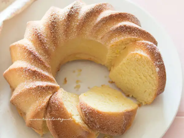 Deliziosa torta di ricotta, soffice e profumata, spolverata di zucchero a velo su un piatto bianco.