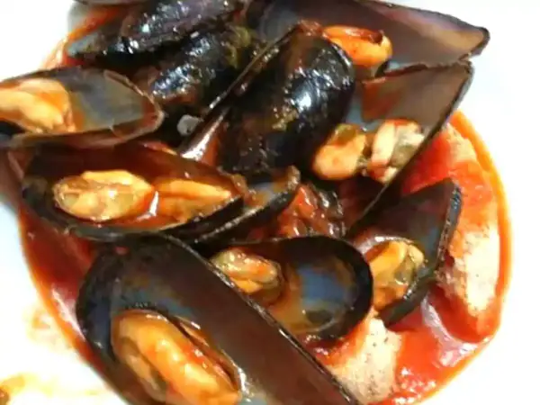 Un invitante piatto di zuppa di cozze al pomodoro, con cozze succulente immerse in un ricco sugo rosso.