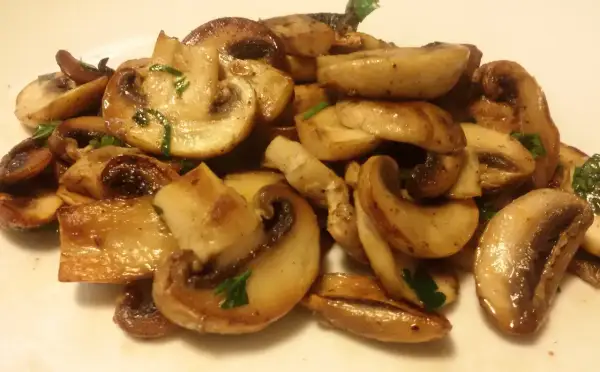 Funghi champignon in padella, dorati e succulenti, guarniti con prezzemolo fresco. Un contorno semplice e gustoso.