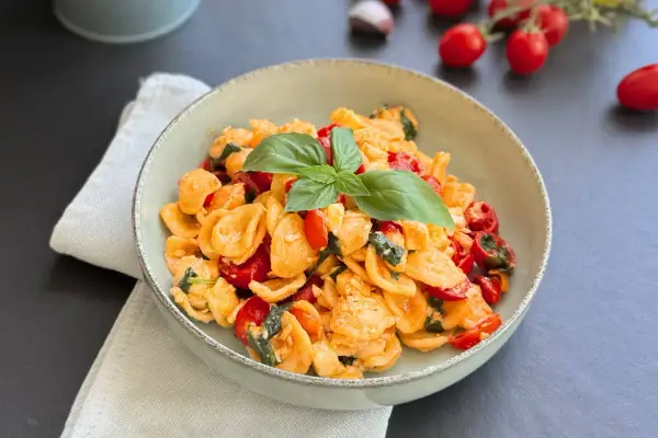 Orecchiette alla crudaiola con pomodorini freschi, basilico e un tocco di formaggio, un piatto estivo da gustare.