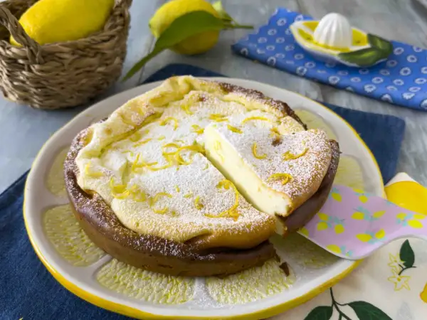 Una deliziosa torta ricotta veloce, spolverata di zucchero a velo e scorza di limone, servita su un piatto a forma di limone.