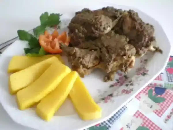 Piatto di coniglio in bianco con polenta e guarnizione di pomodoro e prezzemolo.