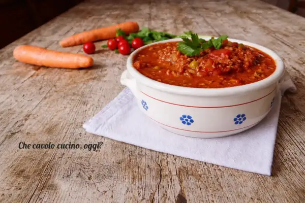 Un invitante sugo con macinato veloce, pronto per condire la pasta. Carote e pomodorini freschi completano la scena.