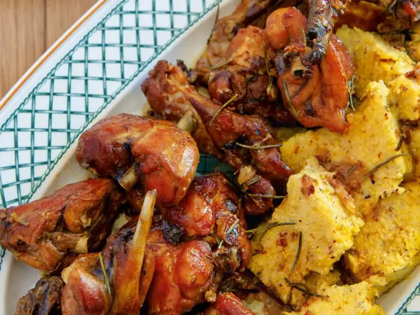 Un saporito coniglio in padella, dorato e aromatico, servito con polenta morbida e rosmarino.