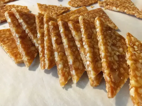 Fette triangolari di croccante di mandorle dorato, con mandorle tritate immerse in caramello lucido.