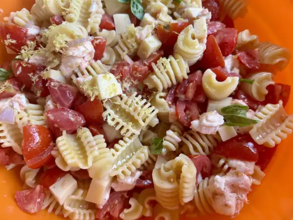 Pasta fredda con pomodoro, mozzarella, gamberetti e scorza di limone, un piatto estivo perfetto.