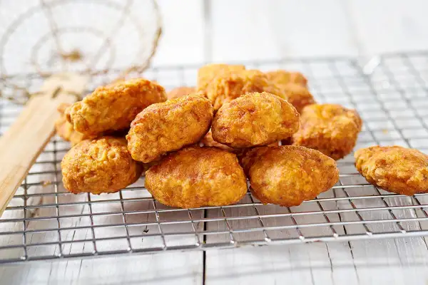 Nuggets fatti in casa dorati e croccanti, appena scolati su una griglia.