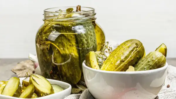Vaso di cetriolini in agrodolce, con alcuni in una ciotola. Profumo di aneto e spezie.