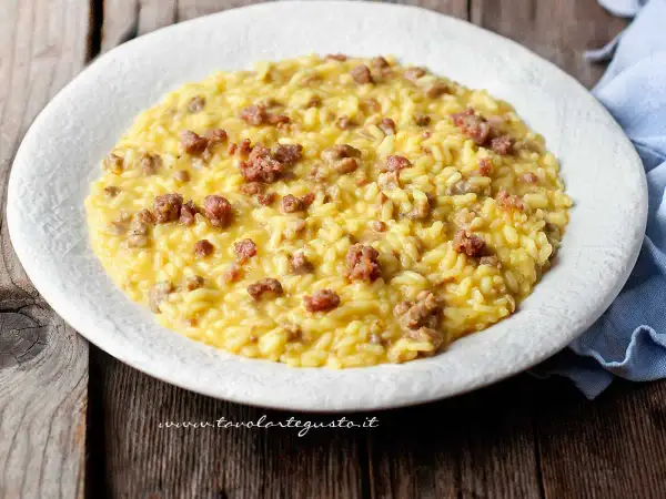 Un cremoso risotto con salsiccia, servito su un piatto bianco, pronto per essere gustato.