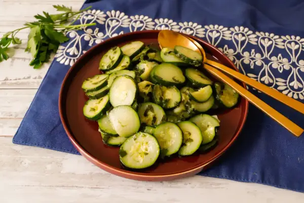 Zucchine trifolate bimby, un contorno semplice e gustoso, servite su un piatto marrone con cucchiai dorati.