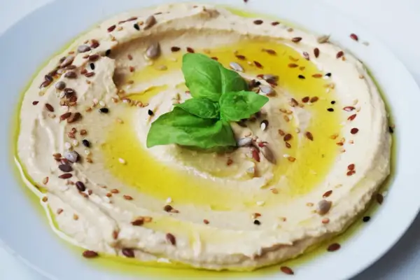 Hummus cremoso con semi misti e basilico, perfetto per idee pranzo veloci e gustose.
