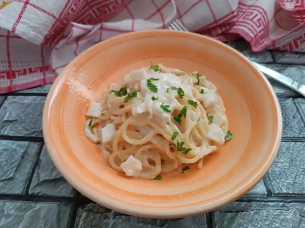 Spaghetti cremosi con cubetti di mozzarella di bufala e prezzemolo fresco, un piatto semplice e delizioso.