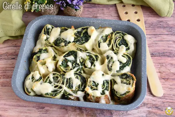 Girelle di crepes con spinaci e formaggio filante, un piatto invitante e gustoso.