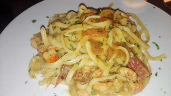 Un piatto invitante di tagliolini agli scampi, con pasta fresca e succulenti crostacei in una cremosa salsa, guarnito con prezzemolo tritato.